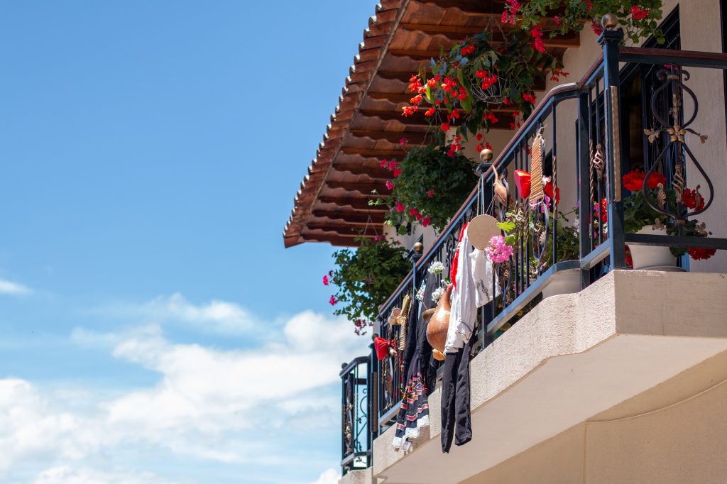 Balcony of an old house decorated with flowers and stuff about Colombian culture and festivity.